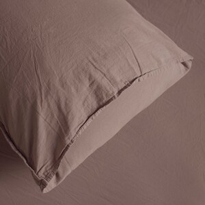 May include: A close-up of a soft, light brown pillowcase with a subtle texture. The fabric is smooth and appears to be made of cotton.