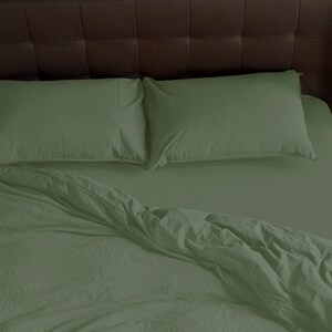 May include: A green bed with a white headboard and two green pillows. The bed is made with a green duvet cover and a white sheet.