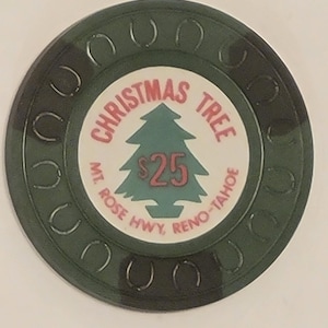 May include: A green casino chip with a Christmas theme. The center features a green Christmas tree graphic with the text "CHRISTMAS TREE" and "MT. ROSE HWY, RENO-TAHOE". The chip has a horseshoe design around the edge.