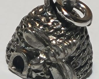 May include: A silver-toned charm shaped like a beehive, featuring a detailed textured surface. The charm includes a small loop for attachment and a bee design. The charm is designed to be used as a pendant or a charm for a bracelet.