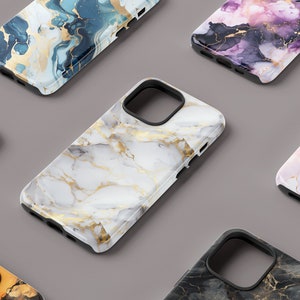 May include: A collection of six phone cases with different marble and abstract designs. The cases are all black with a clear plastic back that shows the design. The designs include white and gold marble, blue and gold marble, pink and gold marble, black and gold marble, and a blue and gold abstract design.
