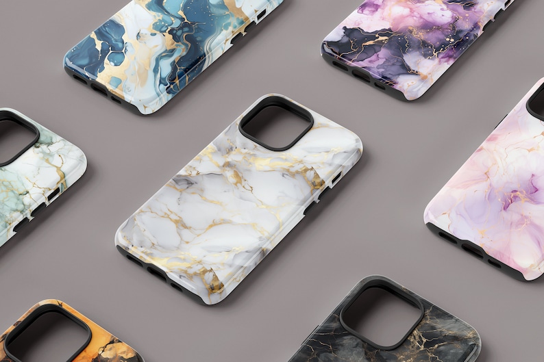 May include: A collection of six phone cases with different marble and abstract designs. The cases are all black with a clear plastic back that shows the design. The designs include white and gold marble, blue and gold marble, pink and gold marble, black and gold marble, and a blue and gold abstract design.