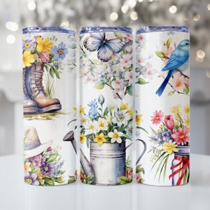 May include: Three stainless steel tumblers with different floral designs. The first tumbler features a bouquet of flowers, a pair of boots, and a hat. The second tumbler features a butterfly, flowers, and a watering can. The third tumbler features a bluebird, flowers, and a jar with a red ribbon.