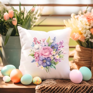 May include: White pillow with a floral design featuring a pink rose and purple flowers. The pillow is on a woven surface with Easter eggs.