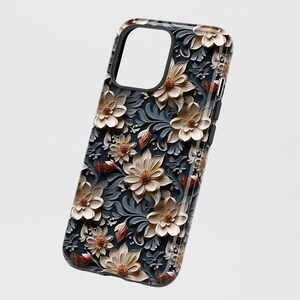 May include: A black phone case with a floral design. The flowers are white and brown with a 3D effect. The background is dark blue.