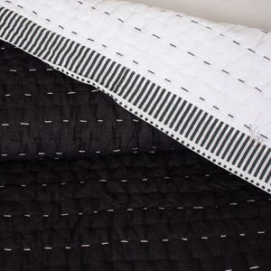 Texture of the lightweight Indian cotton fabric in a solid black, reversible Kantha quilt
