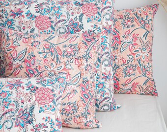 May include: Four decorative throw pillows with a floral pattern in shades of pink, blue, and white. The pillows are arranged in a stack, with the largest pillow on the bottom and the smallest pillow on top.
