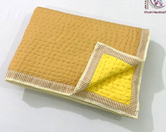 May include: A mustard yellow cotton kantha quilt with a yellow and white striped border. The quilt is folded in half, revealing a bright yellow underside.
