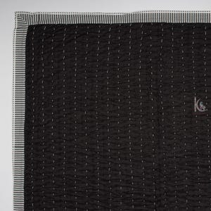 May include: Black quilted blanket with white stitching and a striped border. The blanket has a crinkled texture and a small logo in the bottom right corner. The border is white with black stripes.
