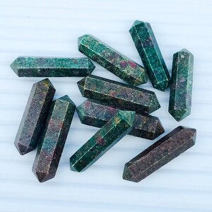 May include: A collection of ten green and red gemstone points, also known as ruby in zoisite, arranged in a cluster on a white surface.