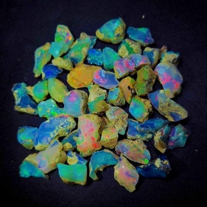May include: A collection of rough, natural opal gemstones in various shades of blue, green, and pink. The opals are iridescent and have a rough, natural texture.