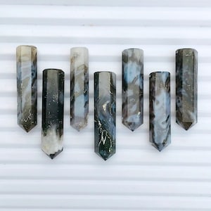 May include: Six grey and white agate crystal points with a hexagonal shape. The points are arranged in a row on a white surface.