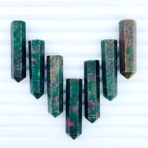 May include: Seven green and red ruby zoisite crystal points, each with a pointed tip and a hexagonal shape.