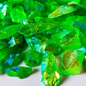 May include: A collection of iridescent green crystal chips. The crystals have a shimmering, rainbow-like effect.