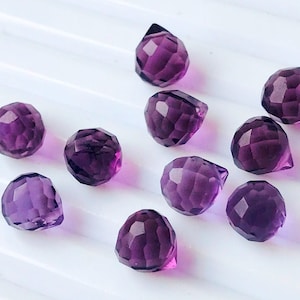 Puede incluir: Diez cuentas de piedra preciosa de amatista facetadas en forma de lágrima. Las cuentas son de color morado oscuro y tienen un alto brillo.