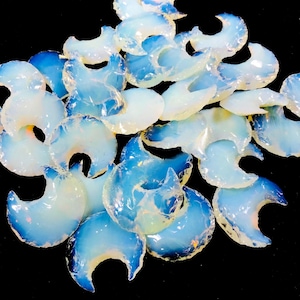 May include: A collection of iridescent opalite crescent moon shaped stones. The stones are translucent and have a milky white color with a hint of blue.