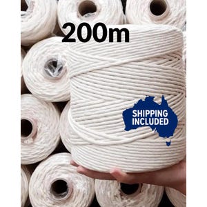 May include: A large spool of off-white macrame cord, with the text "200m" in black. The cord is tightly wound and appears to be made of cotton. Several other spools are visible in the background.