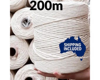 May include: A large spool of off-white macrame cord, with the text "200m" in black. The cord is tightly wound and appears to be made of cotton. Several other spools are visible in the background.
