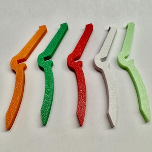 May include: Five plastic clips in different colors: orange, green, red, white, and light green. The clips are all the same shape and size, with a curved design.