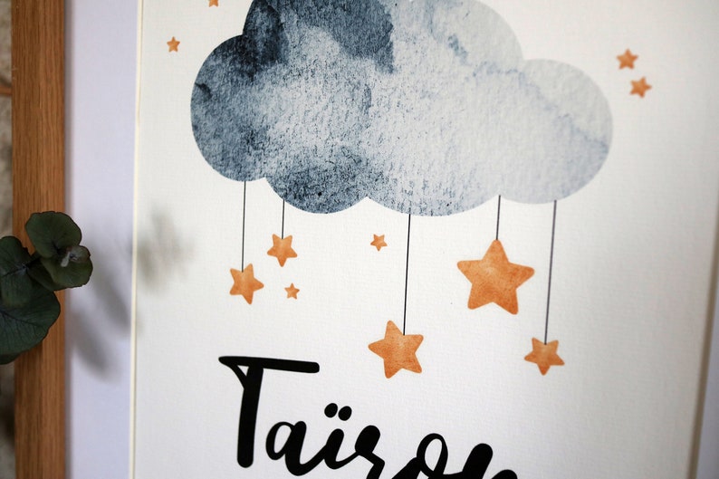 Puede incluir: Una impresi&oacute;n de acuarela con una nube gris y estrellas naranjas colgando de ella. El texto "Tairs" est&aacute; escrito en cursiva negra en la parte inferior de la impresi&oacute;n.