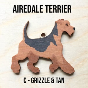 May include: A wooden cutout of an Airedale Terrier dog in a grizzle and tan color scheme. The dog is standing on all four legs with its tail curled up. The cutout is labeled "C - Grizzle & Tan".
