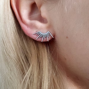 Op de afbeelding: Een paar zilveren oorbellen met een zonnestralenontwerp. De oorbellen zijn klein en delicaat en zouden een geweldige aanvulling zijn op elke sieradencollectie.