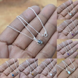Puede incluir: Un conjunto de diez collares de plata con colgantes de piedras preciosas de forma ovalada. Las piedras preciosas son de varios colores, incluyendo azul, verde, rojo, morado y marrón.