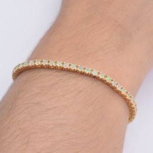 May include: A gold tennis bracelet with white opal stones.
