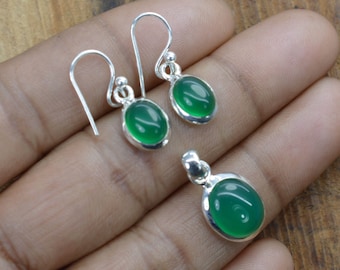 May include: A set of green gemstone earrings and a pendant necklace. The earrings and pendant are made of sterling silver and feature oval-shaped green gemstones.
