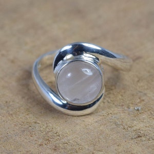 Peut inclure: Une bague en argent avec une pierre précieuse en quartz rose. La bague a un design unique et torsadé.
