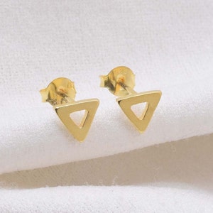 May include: A pair of gold triangle stud earrings. The earrings are simple and minimalist, with a hollow triangle design.