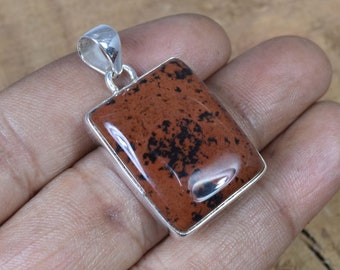 May include: A square pendant with a brown and black jasper stone set in sterling silver. The pendant has a polished finish and is ready to be worn on a necklace.