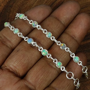 May include: Two silver chain bracelets with opal gemstones. Each bracelet has a clasp closure.