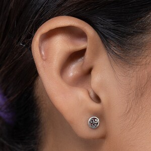 May include: Silver stud earrings with a circular design featuring a Celtic knot pattern.