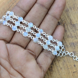 May include: A silver chain bracelet with multiple strands of round moonstone beads. The bracelet has a lobster clasp closure.