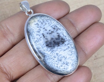 Pode incluir: Um pingente de prata com uma pedra de opala dendrítica branca e preta. A pedra tem formato oval e tem uma argola de prata.