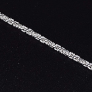 Könnte beinhalten: Eine silberfarbene Halskette mit Box-Link-Design. Die Kette wird vor einem schwarzen Hintergrund gezeigt, der ihren metallischen Glanz und ihr kompliziertes Muster hervorhebt. Die Halskette ist ein Schmuckstück.