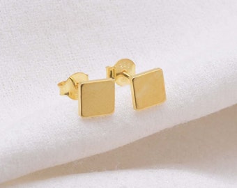 May include: A pair of gold square stud earrings. The earrings are small and simple, and they would make a great everyday accessory.