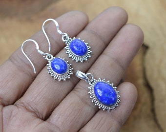 Puede incluir: Un conjunto de pendientes y un colgante de plata de ley con piedras preciosas de lapislázuli de forma ovalada. Las piedras preciosas son de color azul intenso y están rodeadas por un diseño de filigrana de plata.