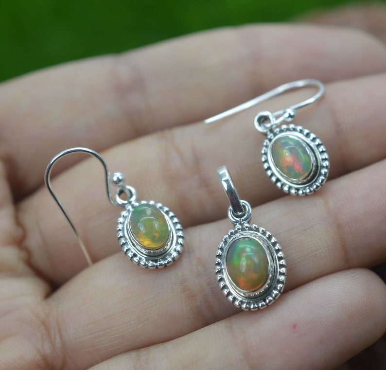 Puede incluir: Un conjunto de pendientes y un colgante de plata de ley con piedras preciosas de &oacute;palo de forma ovalada. Los pendientes tienen un cierre de gancho y el colgante tiene una anilla para sujetarlo a una cadena.