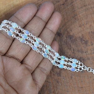 May include: A silver bracelet with three rows of oval-shaped white opal stones.