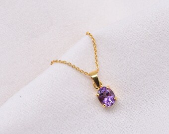 May include: A gold chain necklace with a purple oval gemstone pendant.