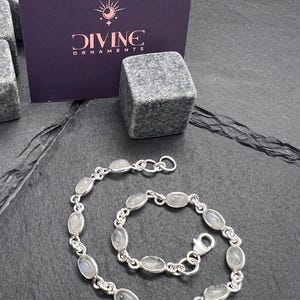 May include: A silver bracelet with oval-shaped moonstone beads. The bracelet is shown with a smaller matching bracelet.