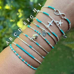 May include: Nine silver bracelets with turquoise beads and various charms, including a heart, a tree, a cross, an infinity symbol, and a starfish. The bracelets are labelled A through I.