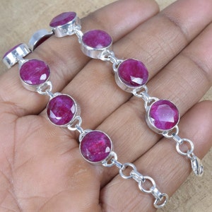 Puede incluir: Un brazalete de plata con un diseño de cadena de eslabones y piedras preciosas redondas de rubí facetadas. El brazalete tiene un cierre de langosta.