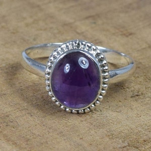 May include: A silver ring with a purple amethyst gemstone set in a beaded bezel.