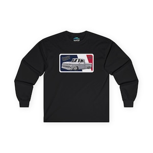 Op de afbeelding: Zwart shirt met lange mouwen met een afbeelding van een klassieke Chevy C10 pick-up truck. De truck is zilverkleurig met een witte rand, tegen een blauw, wit en rode achtergrond. Het woord "CHEVY" staat boven de truck en "C10" rechts.