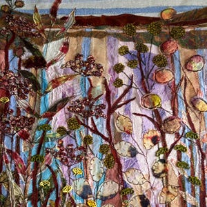 May include: Textile artwork depicting an abstract landscape with vertical stripes in blue, beige, and lilac. The piece incorporates stitched botanical elements in brown, green, and yellow, with a blue and brown sky.
