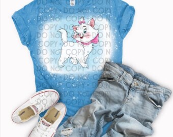 Puede incluir: Una camiseta azul claro con un diseño de blanqueamiento blanco de un gato blanco con un lazo rosa. El gato mira hacia la derecha. La camiseta está encima de un par de pantalones vaqueros azules claros y un par de zapatillas blancas.