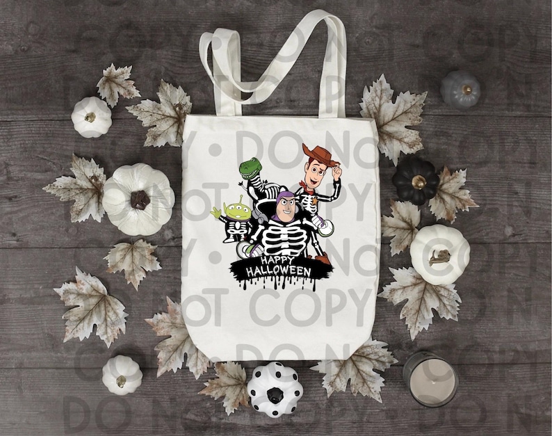 Puede incluir: Una bolsa de tela blanca con un estampado gr&aacute;fico de cuatro personajes de dibujos animados vestidos con disfraces de esqueleto. Los personajes incluyen un vaquero, un guardi&aacute;n espacial, un alien&iacute;gena verde y un dinosaurio. El texto Happy Halloween est&aacute; impreso debajo.